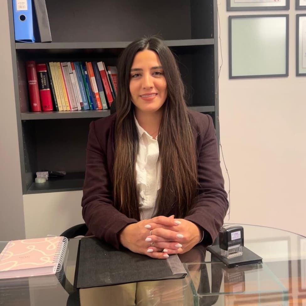 Maria Camarda sentada en su escritorio frente a una biblioteca.